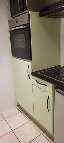 une cuisine avec des armoires blanches et un four à plaques de cuisson dans l'établissement Maison de Sika, à Ugine