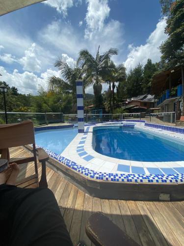 a large swimming pool with a person sitting on a chair next to it at Finca Hotel Santo Tomas El Oasis in Rionegro