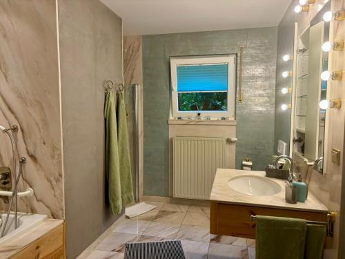 a bathroom with a sink and a tub and a window at Ferienapartments Engeln Eifel in Kempenich