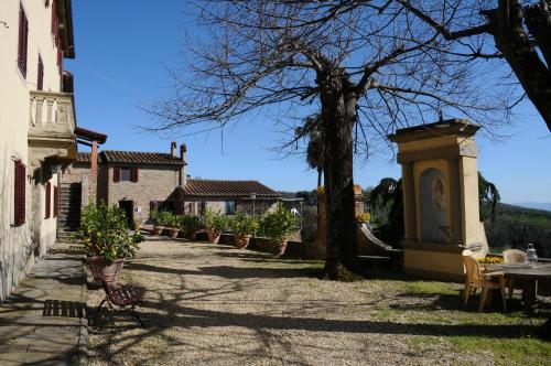 a courtyard of a house with a tree and a table at Agriturismo La Gioconda in Vinci