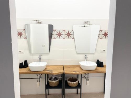 a bathroom with two sinks and two mirrors at Masseria Vico in Villaggio Resta