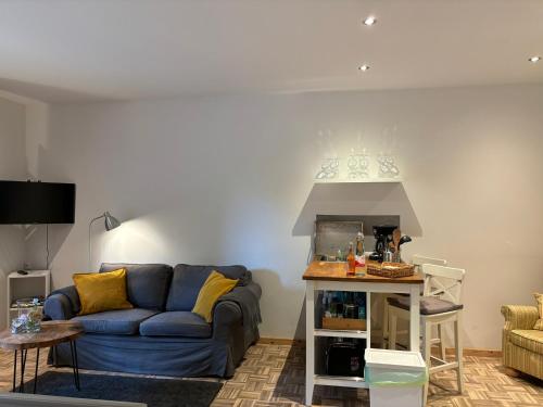 a living room with a blue couch and a table at Ferienapartments Engeln Eifel in Kempenich
