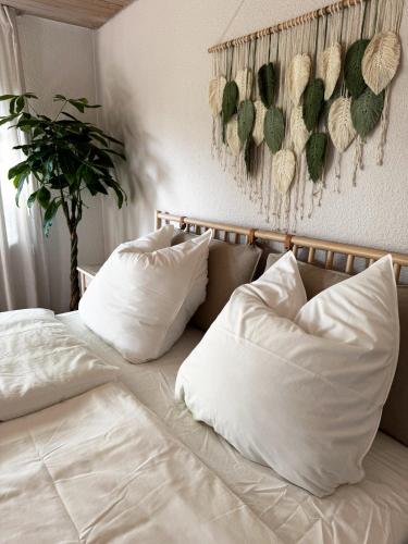 a bed with white pillows and a plant on the wall at Ferienwohnung Wiesental in Kohlstetten
