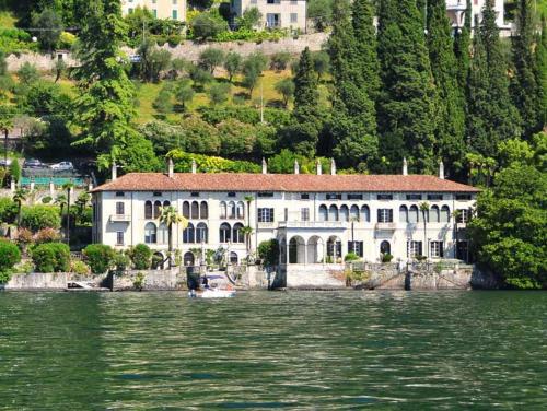 a large white house on the shore of a body of water at Trilly House in Perledo