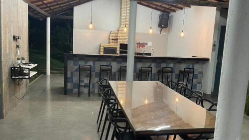 a kitchen with a table and a bar with chairs at Hospedagem em Meio a Natureza em Aperibé in Aperibé