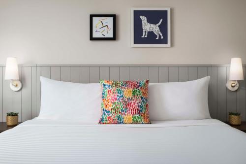 a bedroom with a white bed with a colorful pillow at Sonesta ES Suites Toronto Markham in Markham