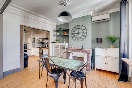 une salle à manger avec une table, des chaises et une horloge dans l'établissement L'Industriel - parking, climatisation, wifi, à Toulouse