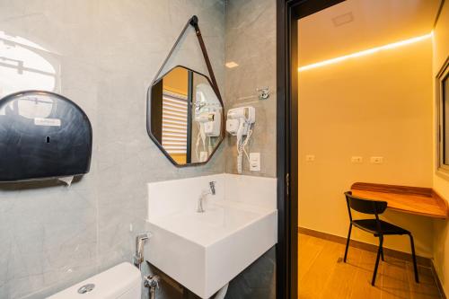 a bathroom with a sink and a mirror and a chair at Hotel Oly Plaza in Piracicaba