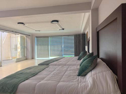 a bedroom with a large bed with green pillows at FIKA Apartamentos Elite in Toluca
