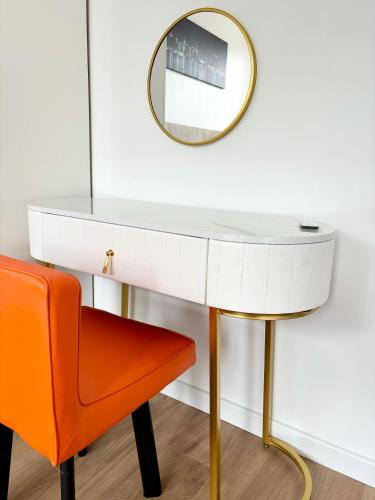 une coiffeuse blanche avec un miroir et une chaise orange dans l'établissement Appartement entier HUI, à Rueil-Malmaison