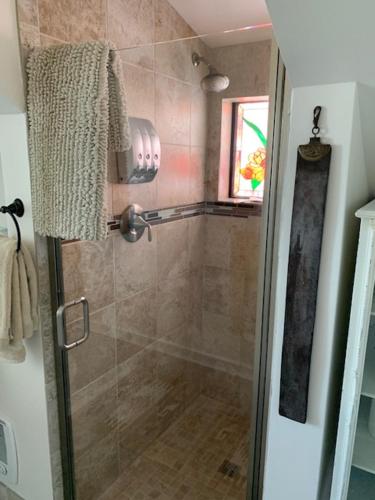 a bathroom with a shower with a glass door at Dungeness Barn House Bed and Breakfast at Two Crows Farm in Sequim