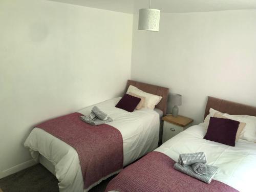 two beds in a small room with towels on them at Middle Cottage Alton Towers, Peak District, JCB in Croxden
