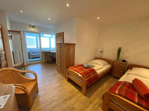 a bedroom with two beds and a chair in it at Schumacher's Landhaus - Bücherhotel in Friedeburg