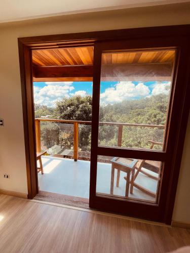 a room with a large window with a table and a view at Pousada Cantinho da Serra in Campos do Jordão