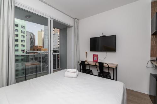 a bedroom with a bed and a desk and a television at 360 Suítes Sé in Sao Paulo