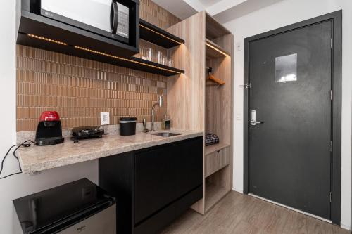 a kitchen with a counter and a black door at 360 Suítes Sé in Sao Paulo