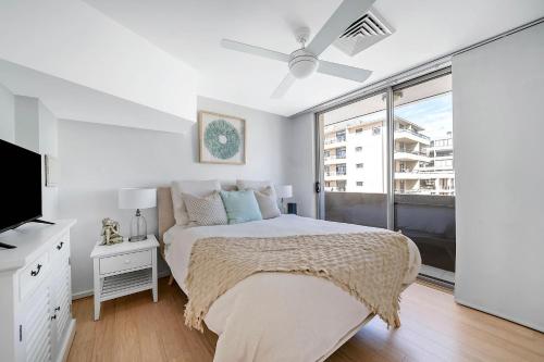 a white bedroom with a bed and a large window at Heart of Manly - Quiet 1 Bed between Beach & Harbour in Sydney