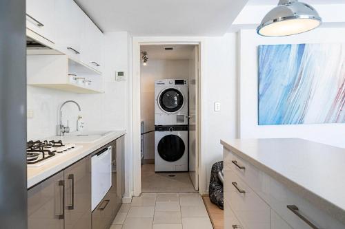 a white kitchen with a washer and dryer in it at Heart of Manly - Quiet 1 Bed between Beach & Harbour in Sydney