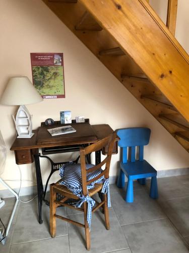 Cette chambre mansardée comprend un bureau et une chaise bleue. dans l'établissement La Liberté dans le Beaujolais, à Lancié