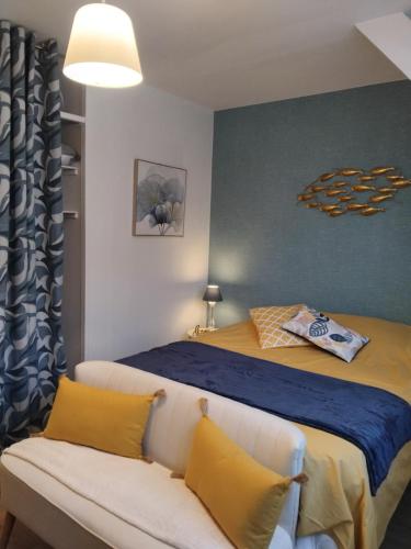 - une chambre avec un lit doté d'oreillers jaunes et d'un canapé dans l'établissement Studio Mer et Centre équestre, à Mers-les-Bains
