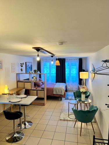 a living room with a bed and a table and chairs at Montbel'appart - Charmant appart T1 tout équipé in Montbéliard