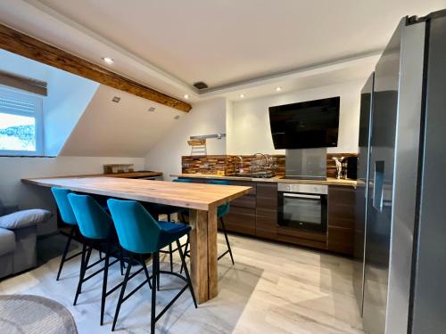 une cuisine avec une table en bois et des chaises bleues dans l'établissement Appart de Robert, nid de luxe au centre-ville, à Gérardmer