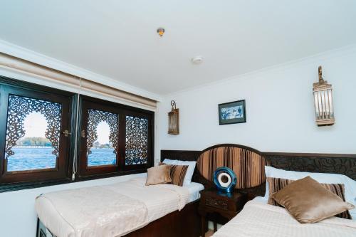 two beds in a room with two windows at Saphir Dahabiya luxury sailing boat Nile cruise Every Saturday from Luxor 4 or 7 nights in Luxor