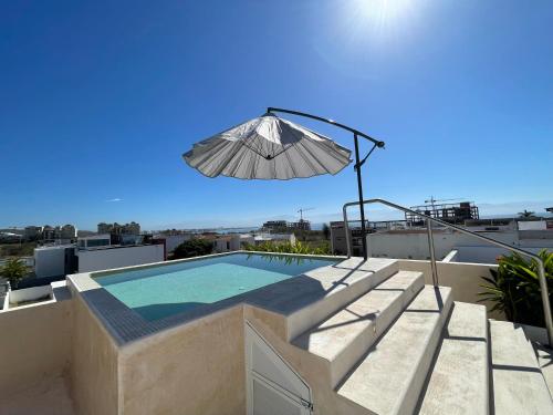 a patio with an umbrella and a swimming pool at BNAYAR Tortugas 38, con acceso al Club de Playa in Cruz de Huanacaxtle