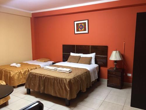 two beds in a room with orange walls at Madison Suite in Tacna