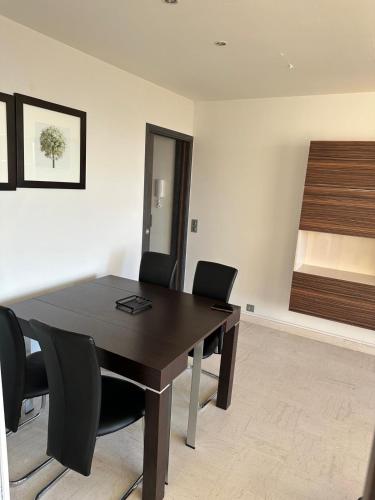 une salle de conférence avec une table en bois et des chaises noires dans l'établissement Joli appartement Face Mer et Plage, Grande Terrasse panoramique, Berck Plage, à 15km du Touquet, à Berck-sur-Mer
