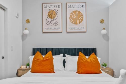 a bed with orange pillows and two posters on the wall at OTR King Bed Free On Site Parking Gym Pool Club Room in Cincinnati
