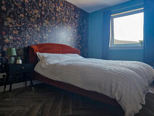 a bedroom with a bed with blue walls and a window at Elegant 2 Bed Flat Perfect for RAH and Airport in Abbotsinch