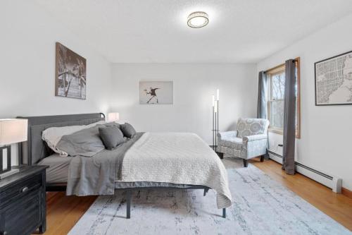 a white bedroom with a bed and a chair at 40 Spacious Sleek Cozy in Middletown
