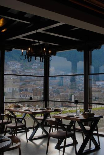 a dining room with tables and chairs and a large window at White House Boutique Hotel & Restaurant - since 1999 in Berat