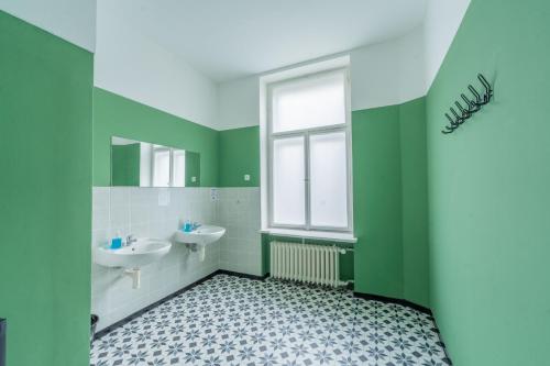 a green bathroom with two sinks and a window at Best Spot Hostel in Prague