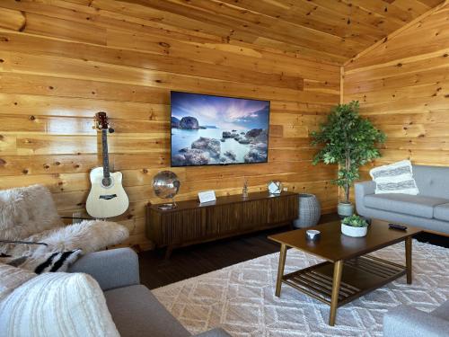 a living room with wooden walls and a guitar at Greywood Reserve in Rogers