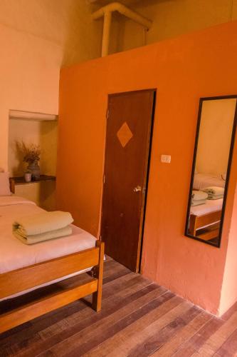 a room with a bed and a mirror and a door at Loki Cusco in Cusco