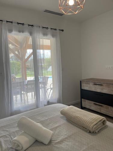 - un lit avec une serviette blanche et une fenêtre dans l'établissement Villa Pourpre-Piscine Chauffée-Climatisation-Jardin, à Bouniagues