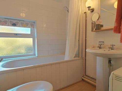 a bathroom with a tub and a toilet and a sink at 1 Hope Cottage in Spilsby