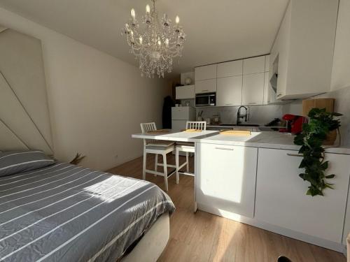 Cet appartement comprend une chambre avec un lit et une cuisine avec un lustre. dans l'établissement Cocon moderne et cosy proche Disneyland et Paris, à Torcy