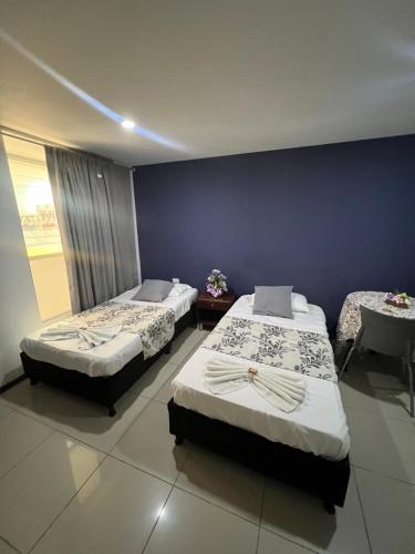 a bedroom with two beds and a blue wall at Hotel Boutique Santa Ana in Cartago