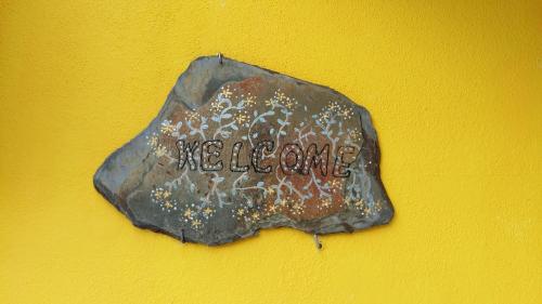 a rock on a yellow wall with the word welcome at My House - Casa Charme in Monchique