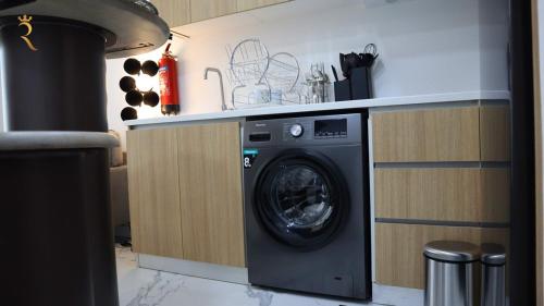 a kitchen with a washing machine under a counter at Terminal 1BR Retreat - Modern Comfort & Chic Stay in Abu Dhabi