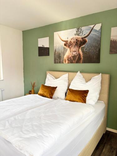 a bedroom with a bed with a cow painting on the wall at Im Herzen der Eifel - Entspannung pur in Hellenthal