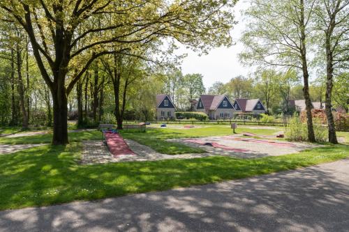 a park with trees and houses in the background at Landhuis op mooi park aan het water in Westerbork