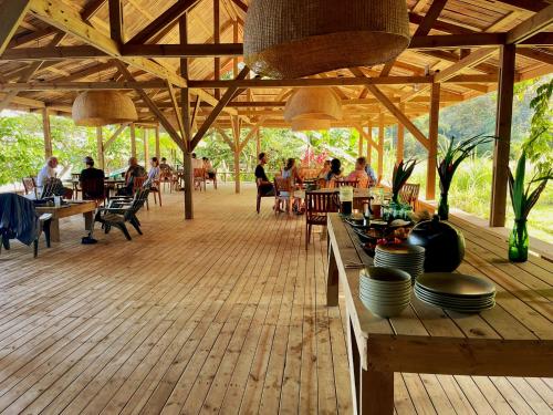 a wooden deck with people sitting at tables in a restaurant at Kurrulau Hotel Playa Pacífica in Nabugá