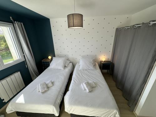 two beds in a small room with a window at GWEL KAER - Maison tout confort petite vue mer in Plouarzel
