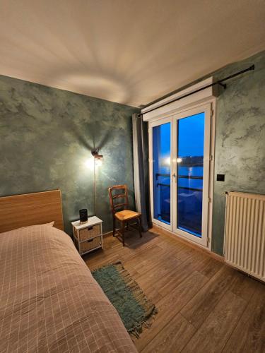 une chambre avec un lit, une fenêtre et une chaise dans l'établissement Appartement en bord de seine, à Ablon-sur-Seine