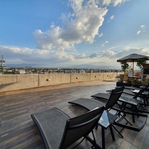 a patio with chairs and tables on a roof at Habitación con baño privado en departamento compartido cerca de zona de conciertos in Mexico City