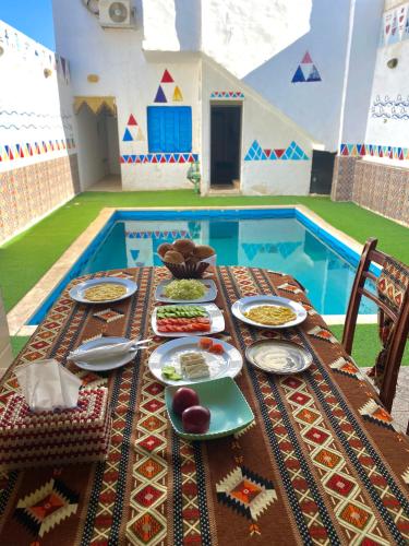a table with plates of food and a swimming pool at Bakar House in Aswan